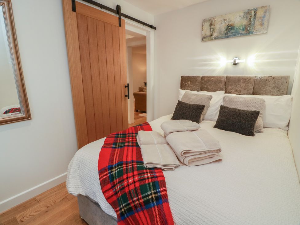 A bedroom with a bed and towels at Rosalin Cottage in Dreghorn near Irvine