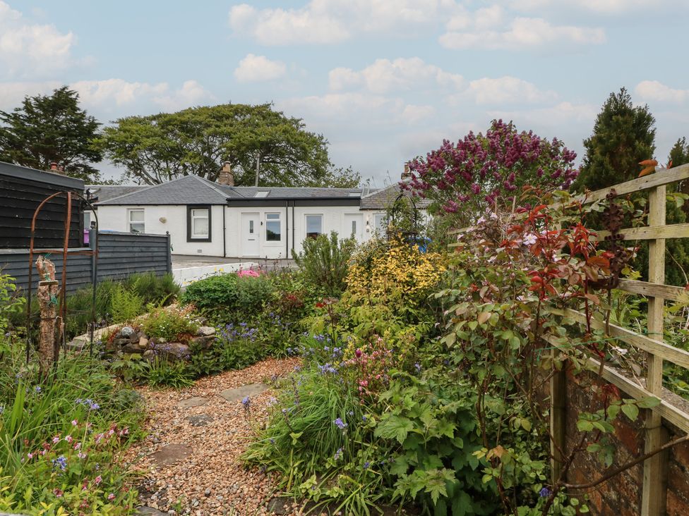 A garden with a gravel path and various flowers at Rosalin Cottage Dreghorn near Irvine