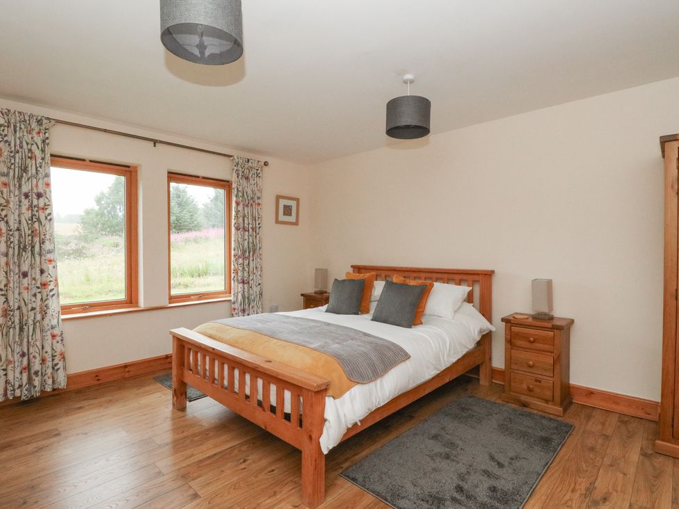 A bedroom with a bed and windows at Taffs Barn Fortrose near Rosemarkie