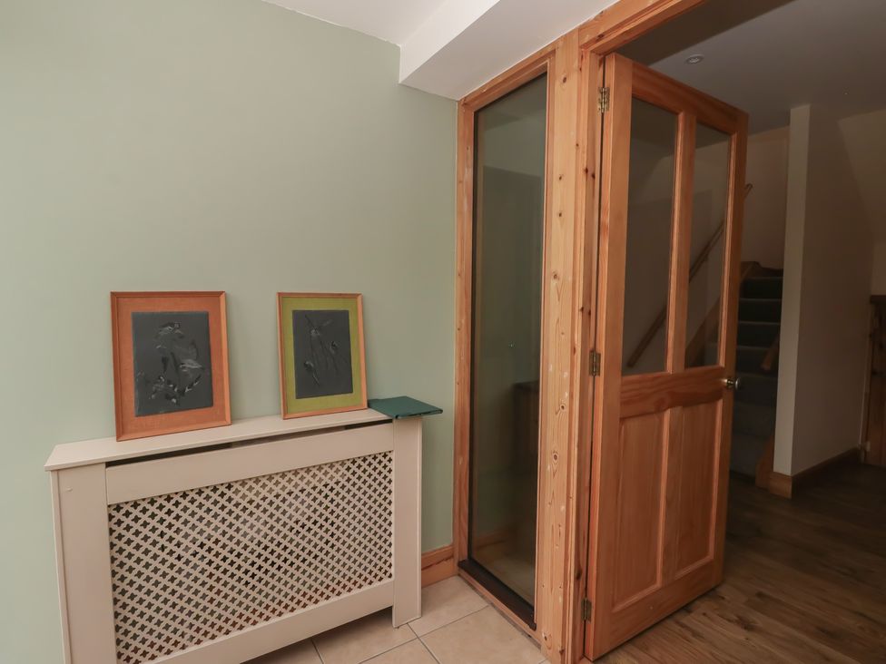 A hallway with a radiator and pictures on the wall at Taffs Barn in Fortrose near Rosemarkie