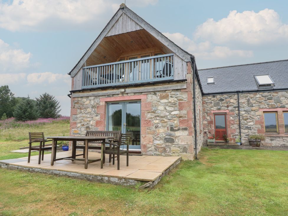 An outdoor patio with a table and chairs at Taffs Barn Fortrose near Rosemarkie