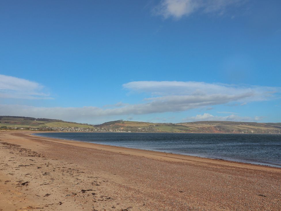 A beach with water and hills in the background at Taffs Barn near Fortrose