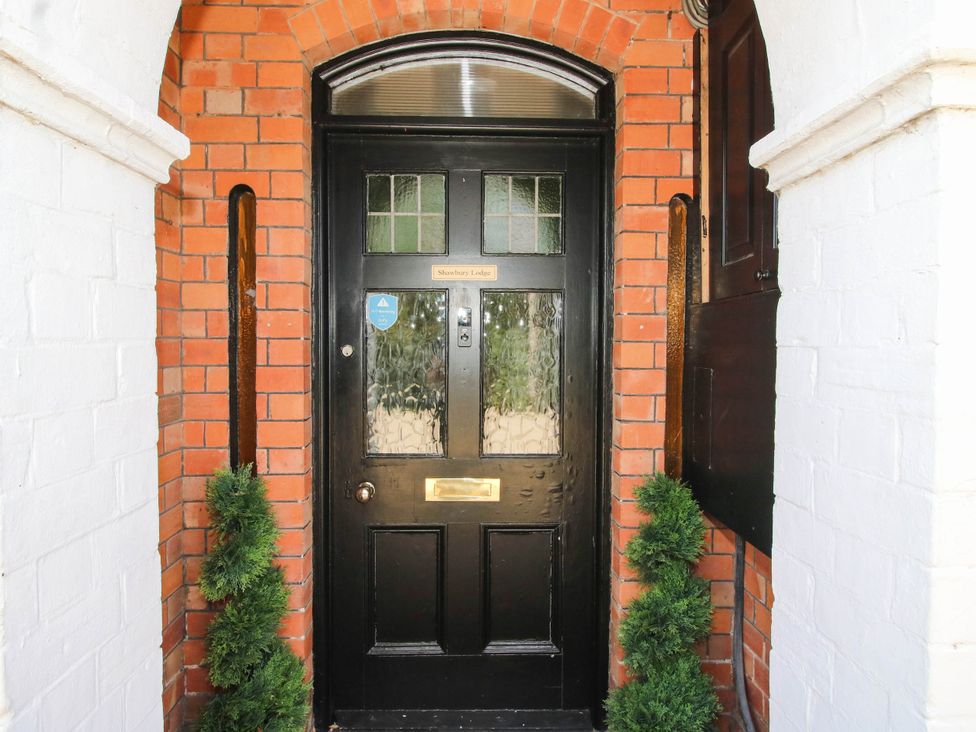 An entrance with a black door and decorative shrubs at The Lodge in Shawbury