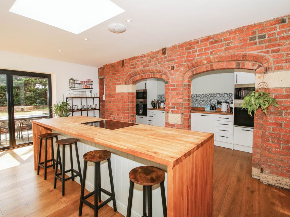 A kitchen with a wooden island and bar stools at The Lodge in Shawbury