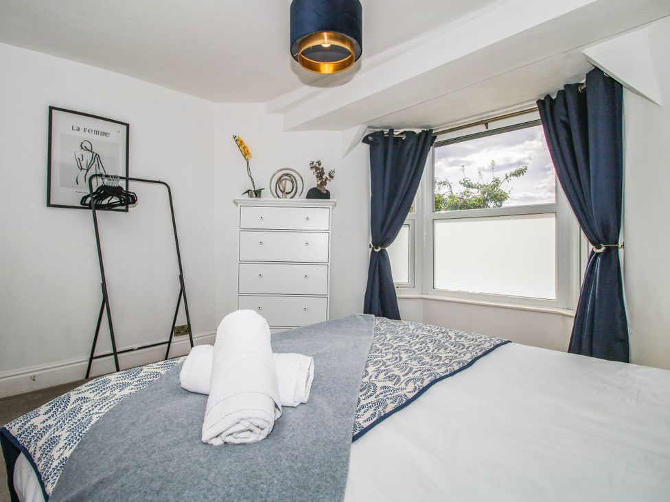 A bedroom with a bed, dresser, and clothes rack at The Lodge in Shawbury