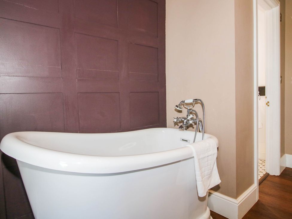 A bathroom with a bathtub and a door at The Lodge in Shawbury