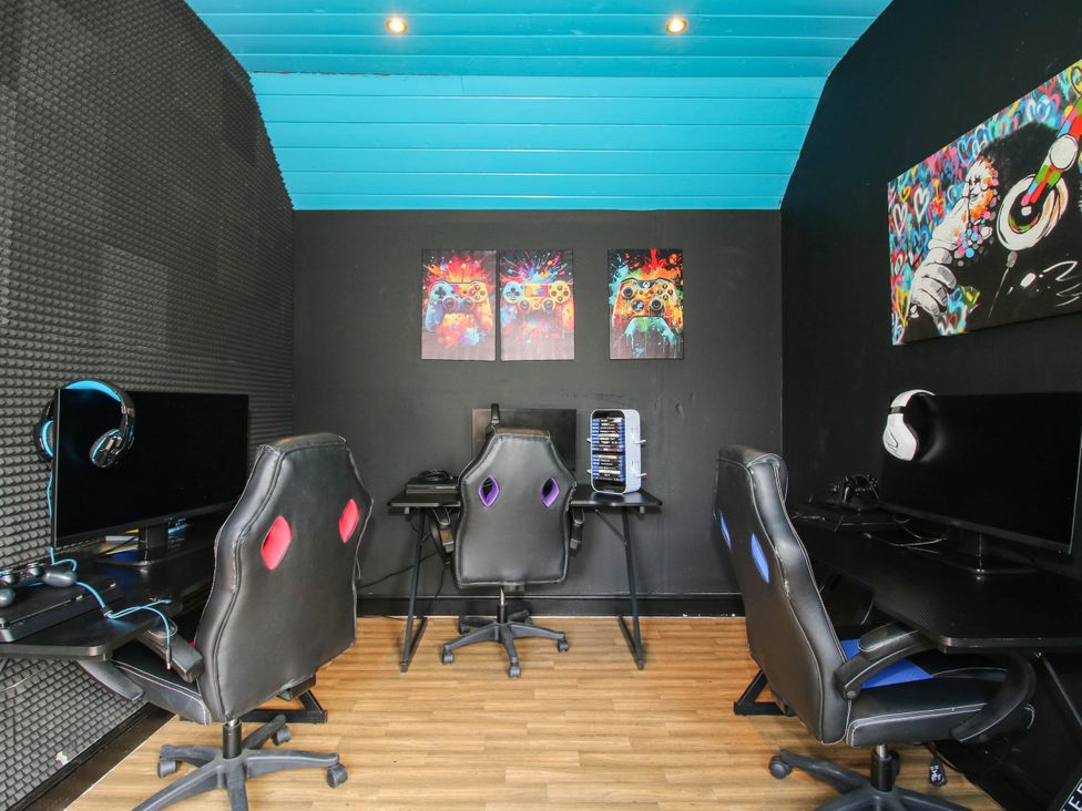 A game room with computer monitors and gaming chairs at The Lodge in Shawbury