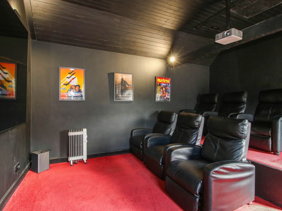 A home theater with black seating and projector at The Lodge in Shawbury