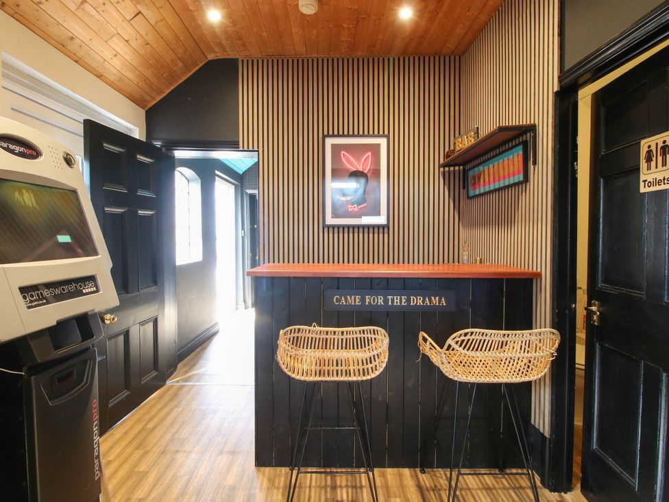 A bar area with stools and games machine at The Lodge in Shawbury