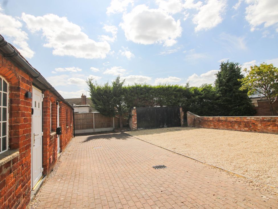 An outdoor parking area with gravel and a brick wall at The Lodge in Shawbury