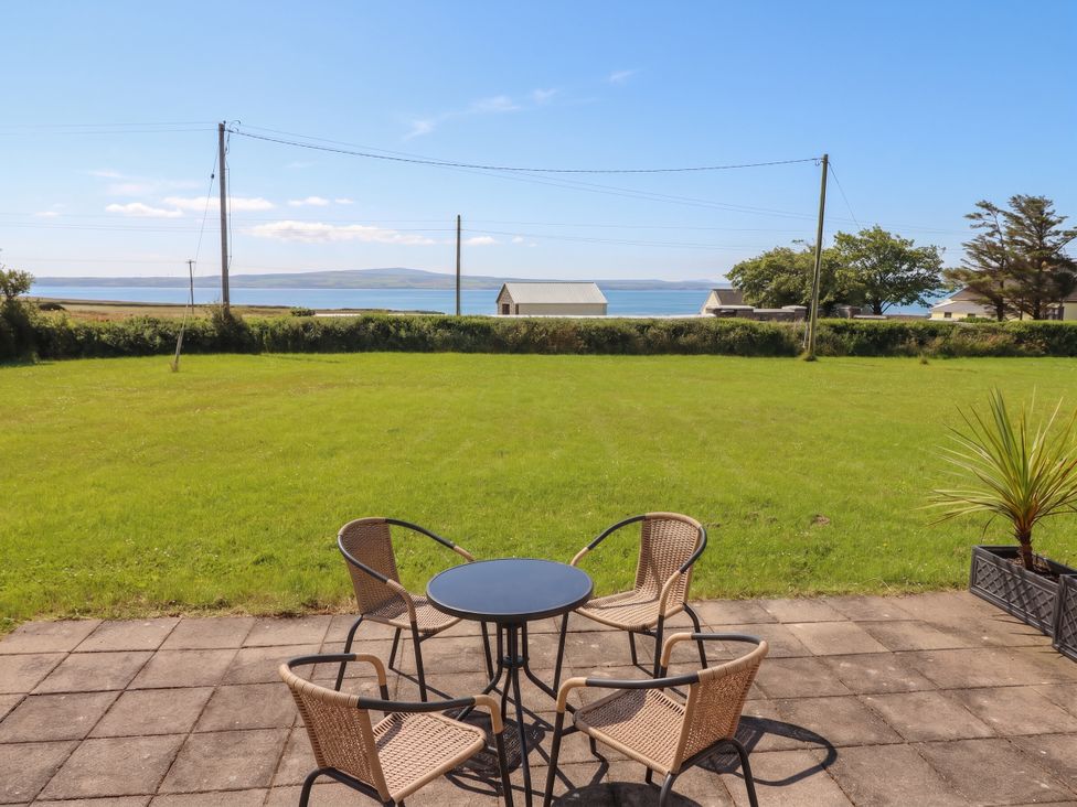 A garden with a table and chairs overlooking the sea at The Boathouse, Carrigaholt, County Clare