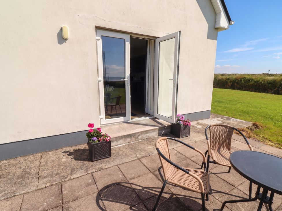 An outdoor area with chairs and a table at The Boathouse in Carrigaholt, County Clare