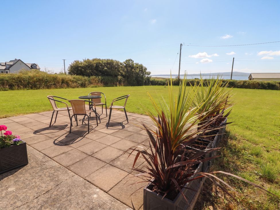 An outdoor seating area with a table and chairs at The Boathouse in Carrigaholt, County Clare