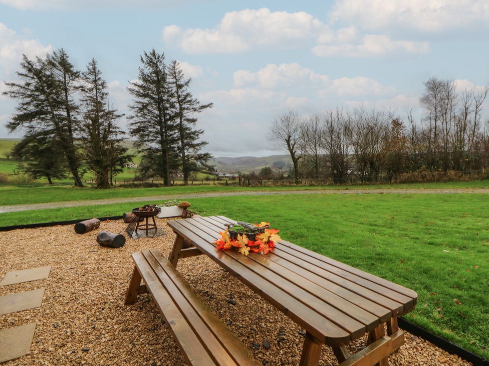 An outdoor area with a picnic table and fire pit at Willow in Llangurig near Llanidloes