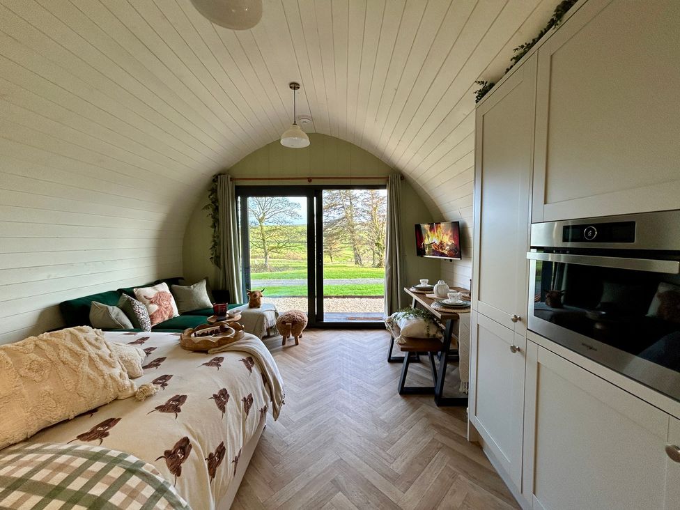A living room with a sofa, dining chair, and kitchen unit at Willow in Llangurig near Llanidloes