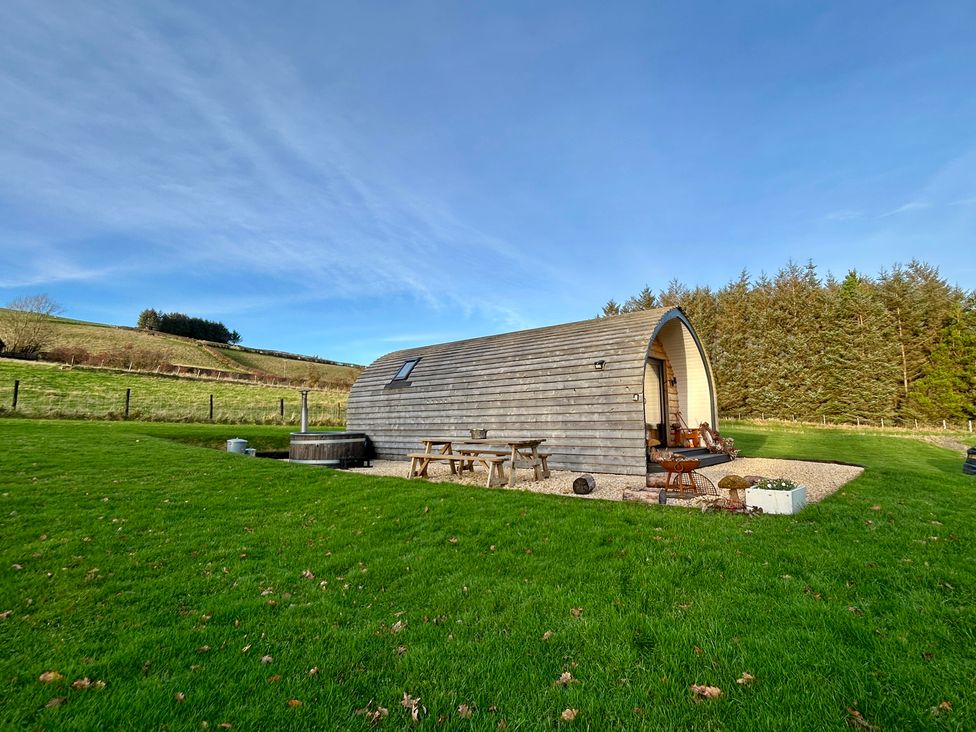 A wooden pod with patio furniture and a hot tub at Willow in Llangurig near Llanidloes
