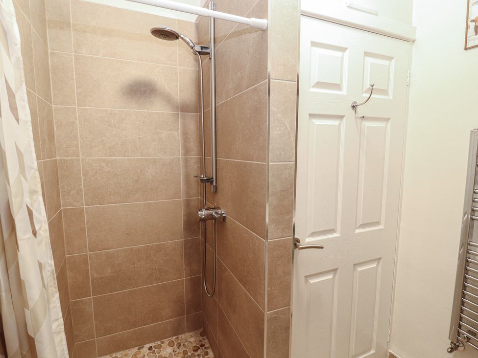 A shower area with a shower head and wall tiles at River Cottage in Eamont Bridge
