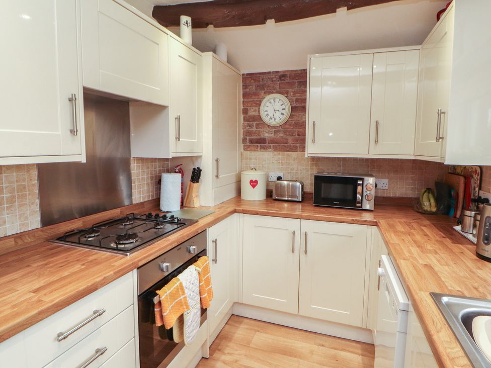 A kitchen with stove, microwave, and cabinets at River Cottage in Eamont Bridge