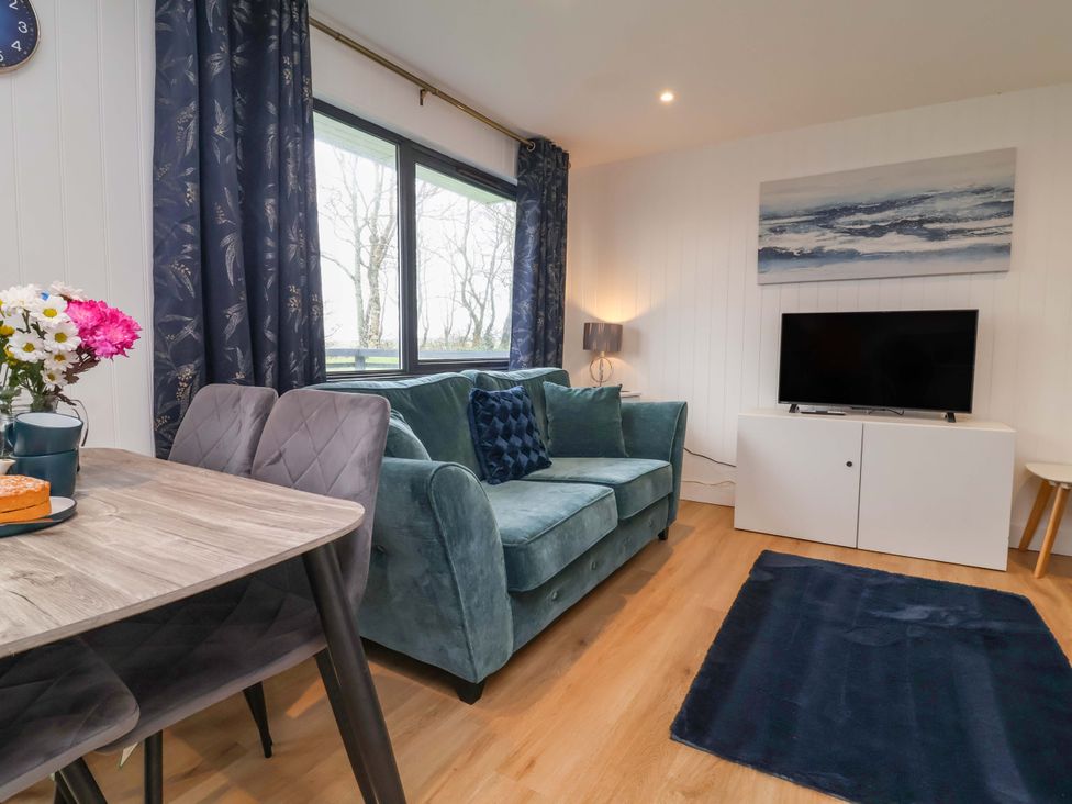A living room with a green sofa and a TV at Cassia in Kilkhampton