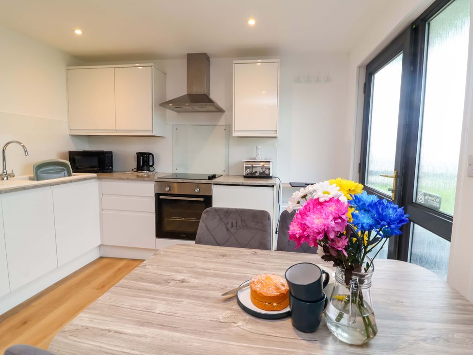 A kitchen with a dining table and flowers at Cassia in Kilkhampton