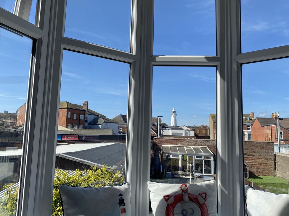 A conservatory with a view of buildings and a lighthouse at 46 The Promenade in Withernsea