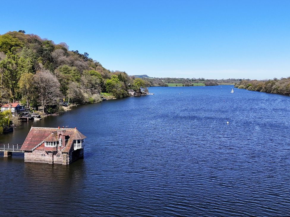 A lake with a boathouse and sailboat at Lady Of The Lake Rudyard Lake