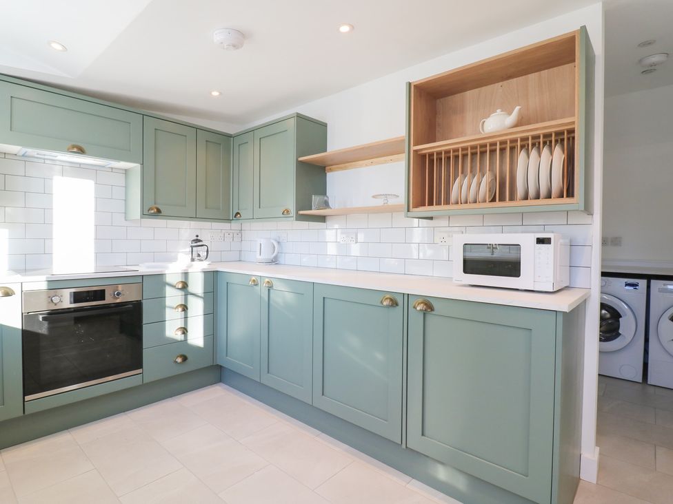 A kitchen with cabinets, oven, microwave and washer at 66 High Street in Cambridge
