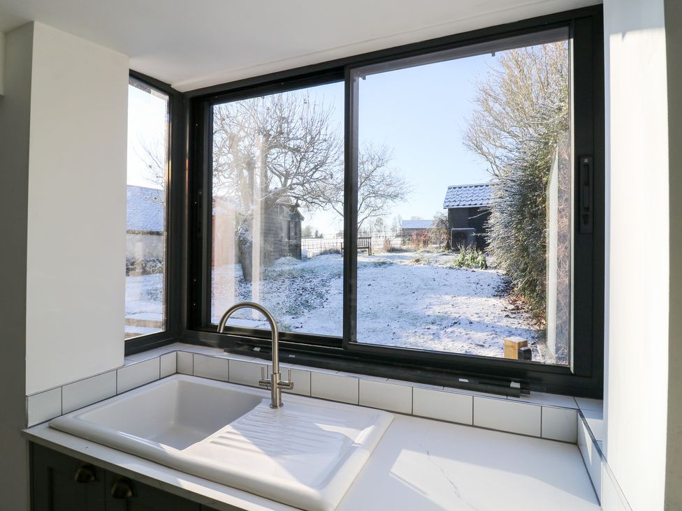 A kitchen sink view overlooking a snowy garden at 66 High Street in Cambridge
