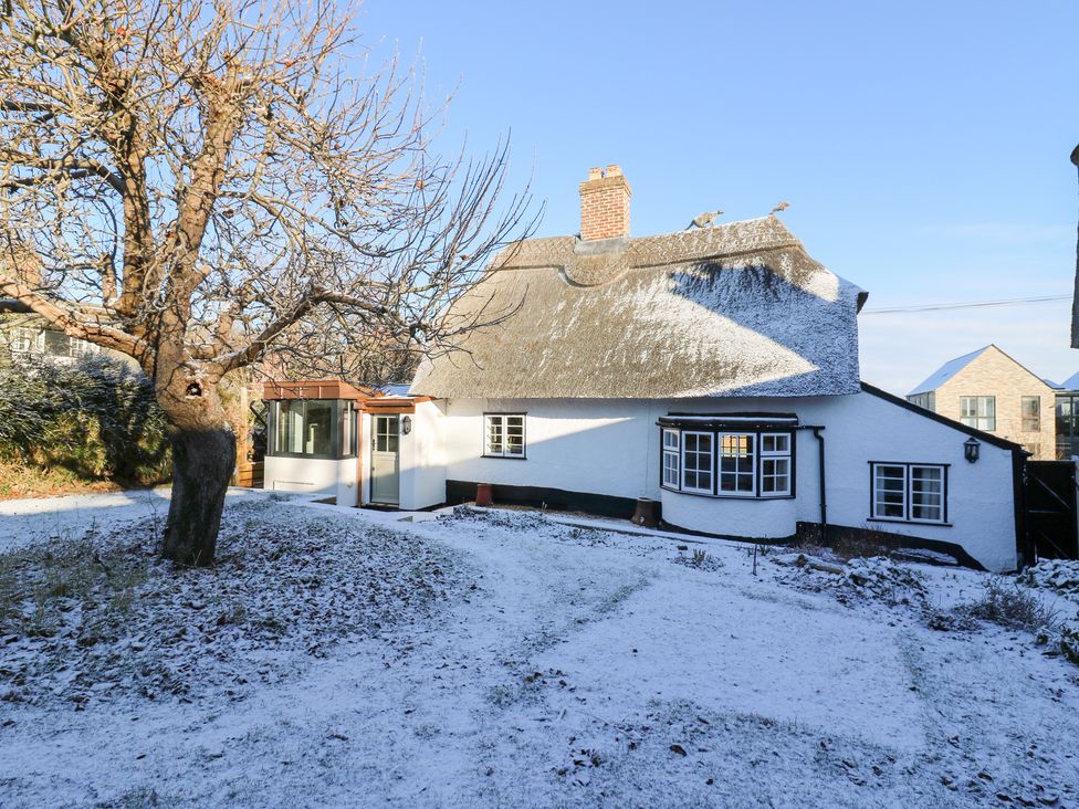 A house with a thatched roof and garden covered in snow at 66 High Street in Cambridge