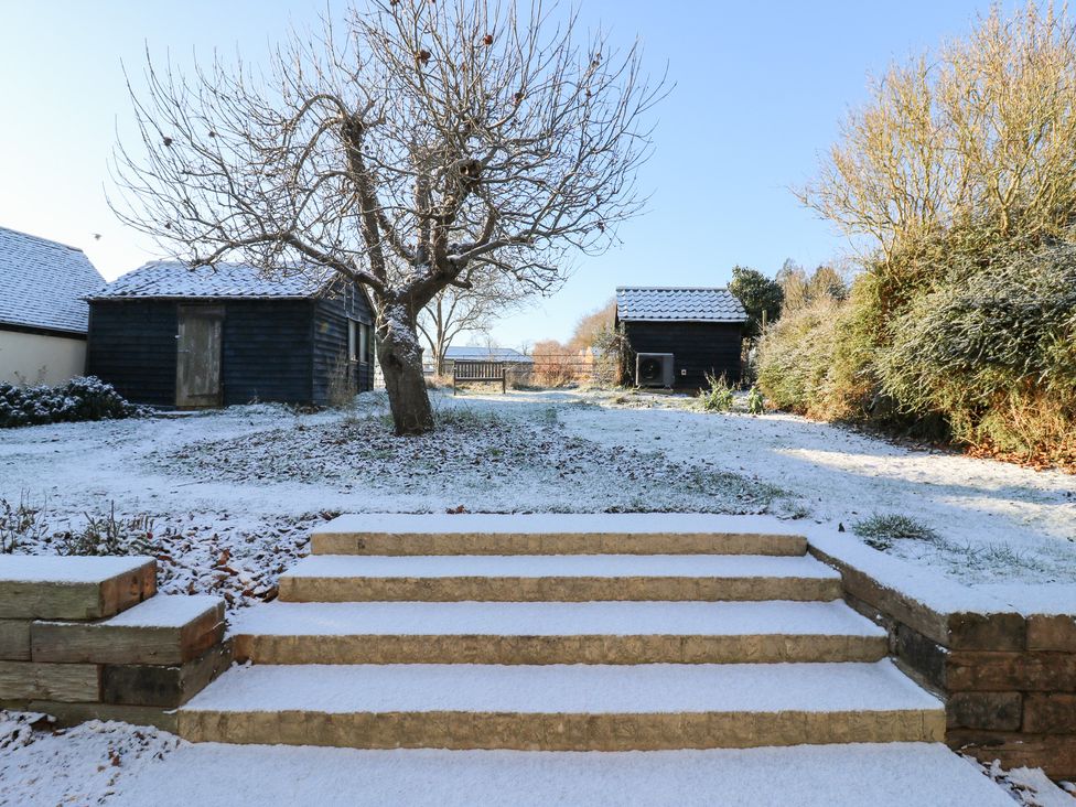 A garden with a tree and shed covered in snow at 66 High Street Cambridge