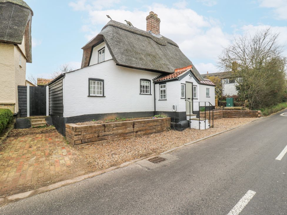 A thatched roof cottage with gravel landscaping at The Old Smithy in Bourn