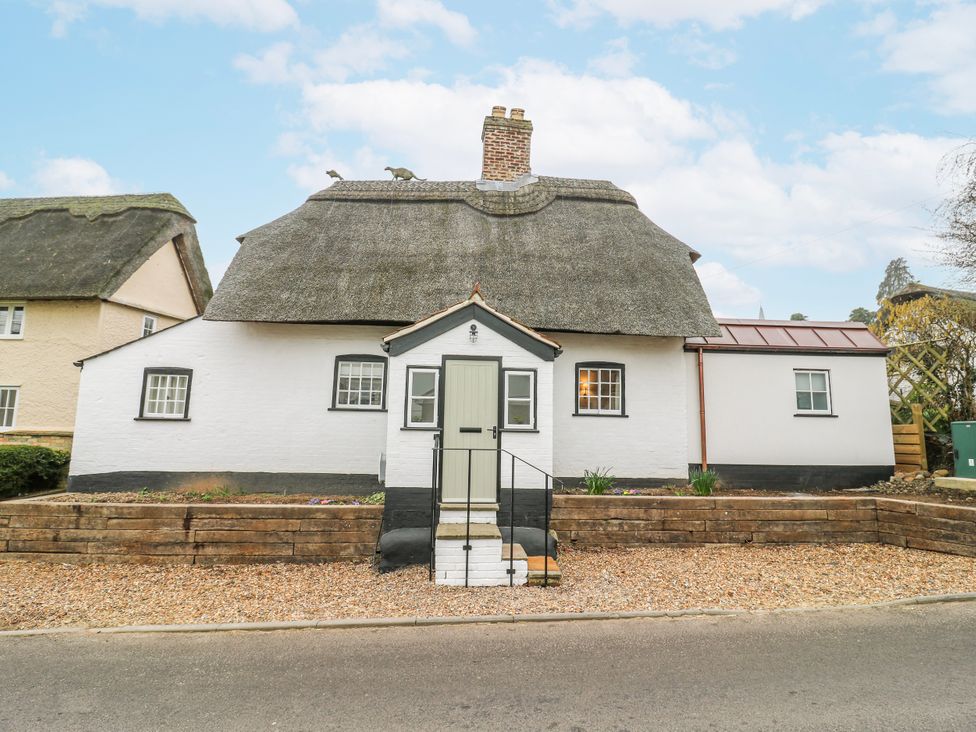 A house with a thatched roof and front door at The Old Smithy in Bourn
