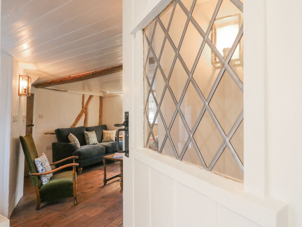 A living room with a sofa and armchair visible through a door at The Old Smithy in Bourn
