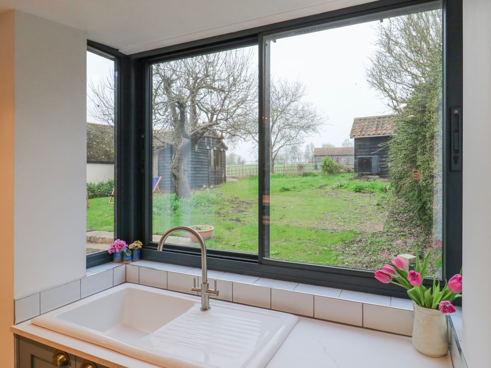 A kitchen with a sink and faucet overlooking a garden at The Old Smithy in Bourn