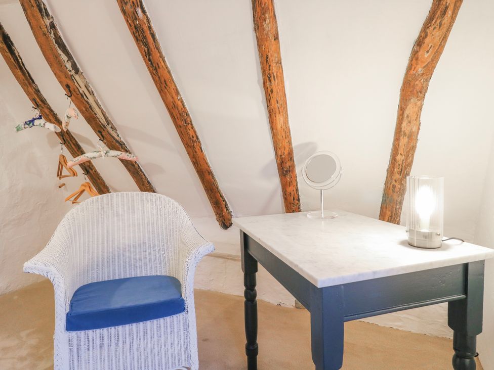 An attic with a chair and a table with a lamp at The Old Smithy in Bourn