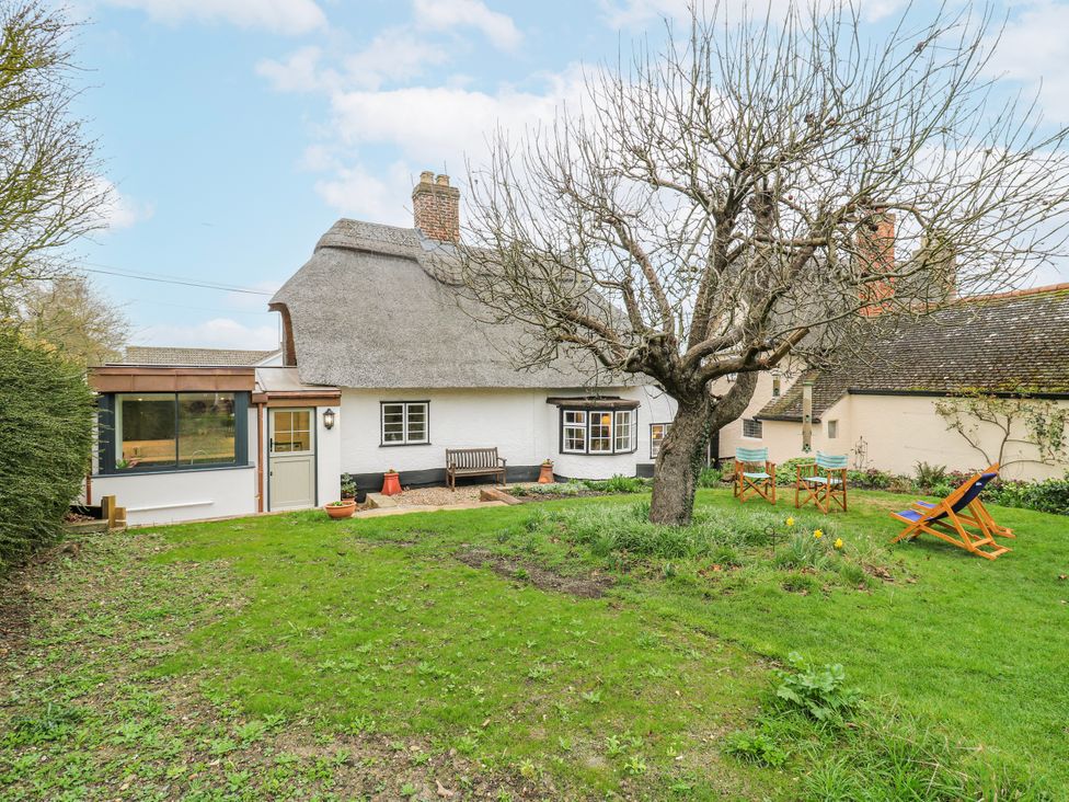 An outdoor view of a house with a garden and seating area at The Old Smithy in Bourn