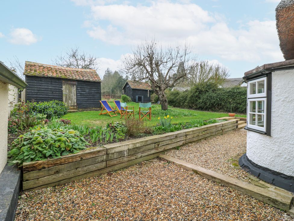 A garden with deck chairs and sheds at The Old Smithy in Bourn