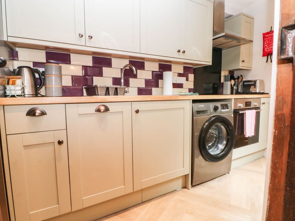 A kitchen with cabinets and appliances including a washing machine at The Cottage O'ergate in Bradwell