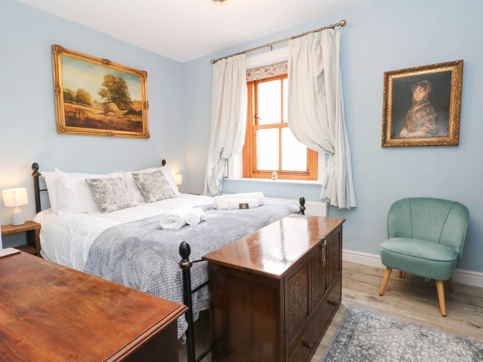 A bedroom with a bed and artwork at The Cottage O'ergate in Bradwell