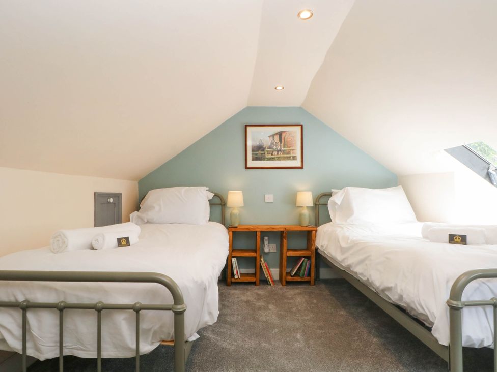 A bedroom with two beds and a nightstand at The Cottage O'ergate in Bradwell