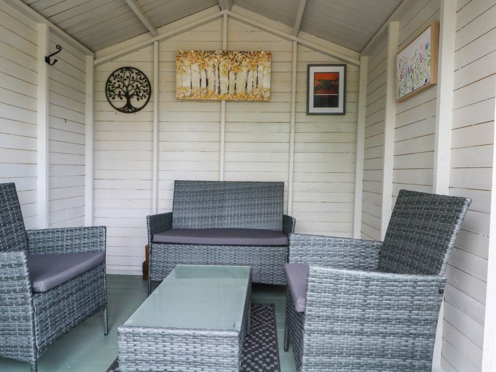 A garden shed with seating area and decorative wall art at The Cottage O'ergate in Bradwell