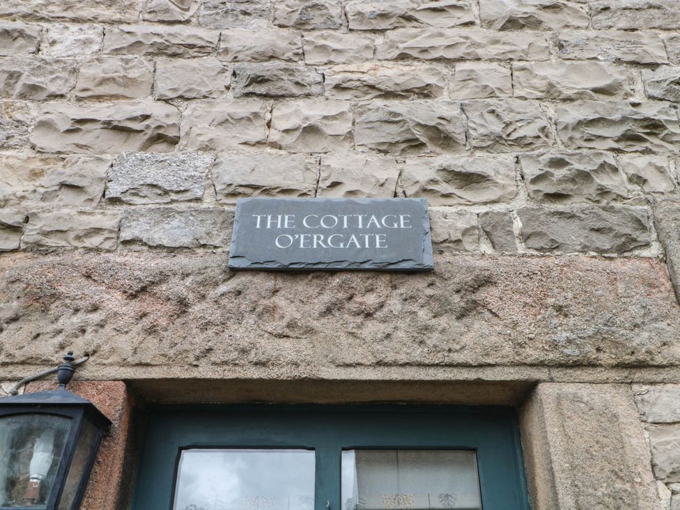 A sign on a stone wall that reads THE COTTAGE O'ERGATE
