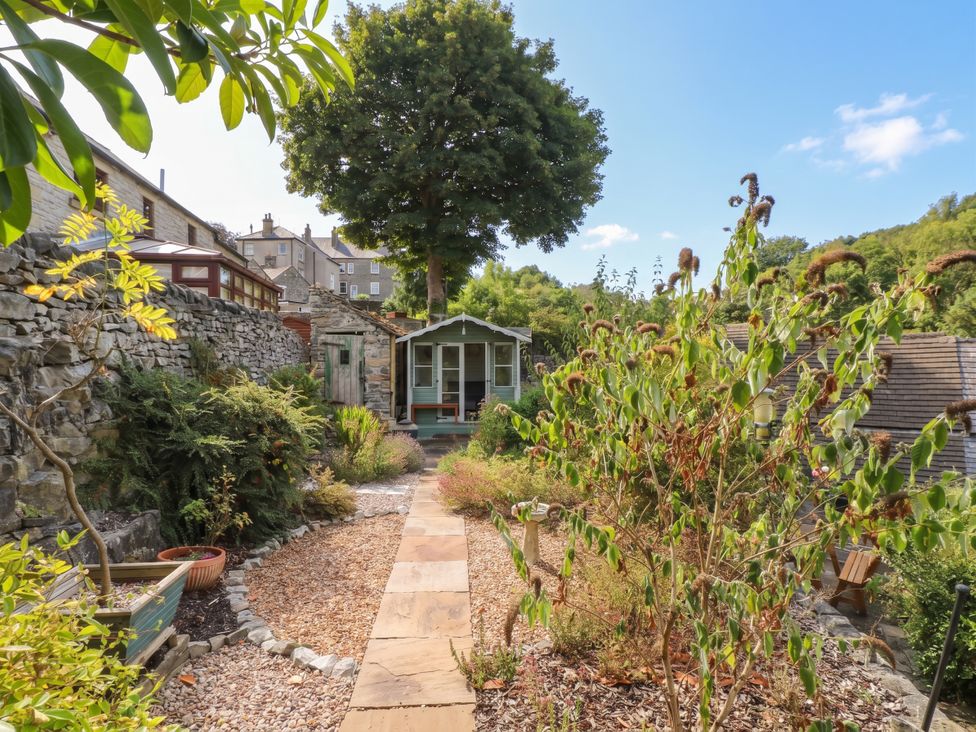 A garden with a pathway and greenhouse at The Cottage O'ergate in Bradwell