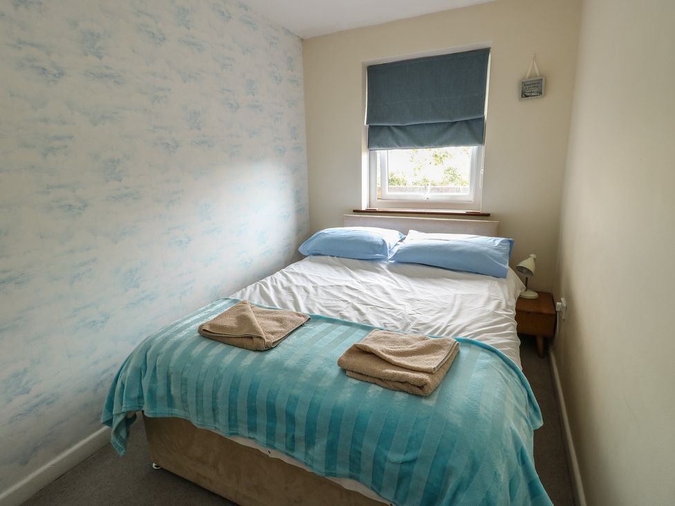 A bedroom with a bed and bedside lamp at Ty Haf in Trearddur Bay