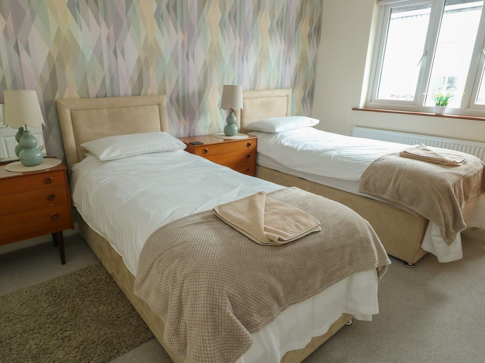 A bedroom with two beds and bedside tables at Ty Haf in Trearddur Bay