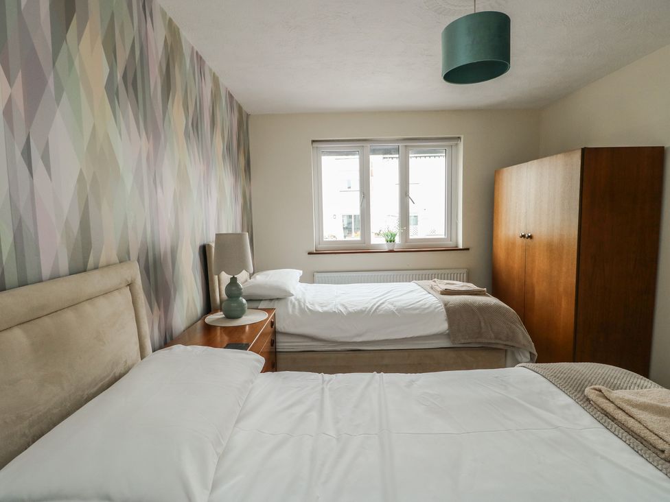 A bedroom with two beds and a wardrobe at Ty Haf in Trearddur Bay