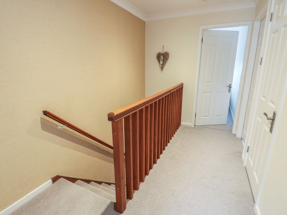 A staircase with handrail and doors in a hallway at Ty Haf in Trearddur Bay