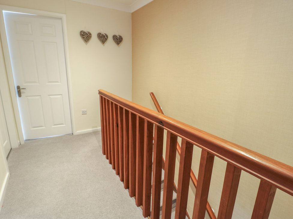 A hallway with a railing and door at Ty Haf in Trearddur Bay