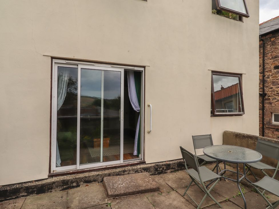 An outdoor area with a sliding door and seating at Flodden Apartment in Wooler