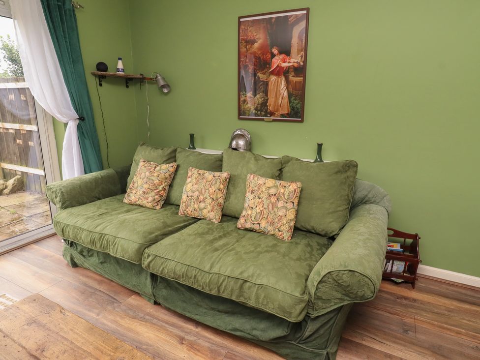 A living room with a green sofa and wall art at Flodden Apartment in Wooler
